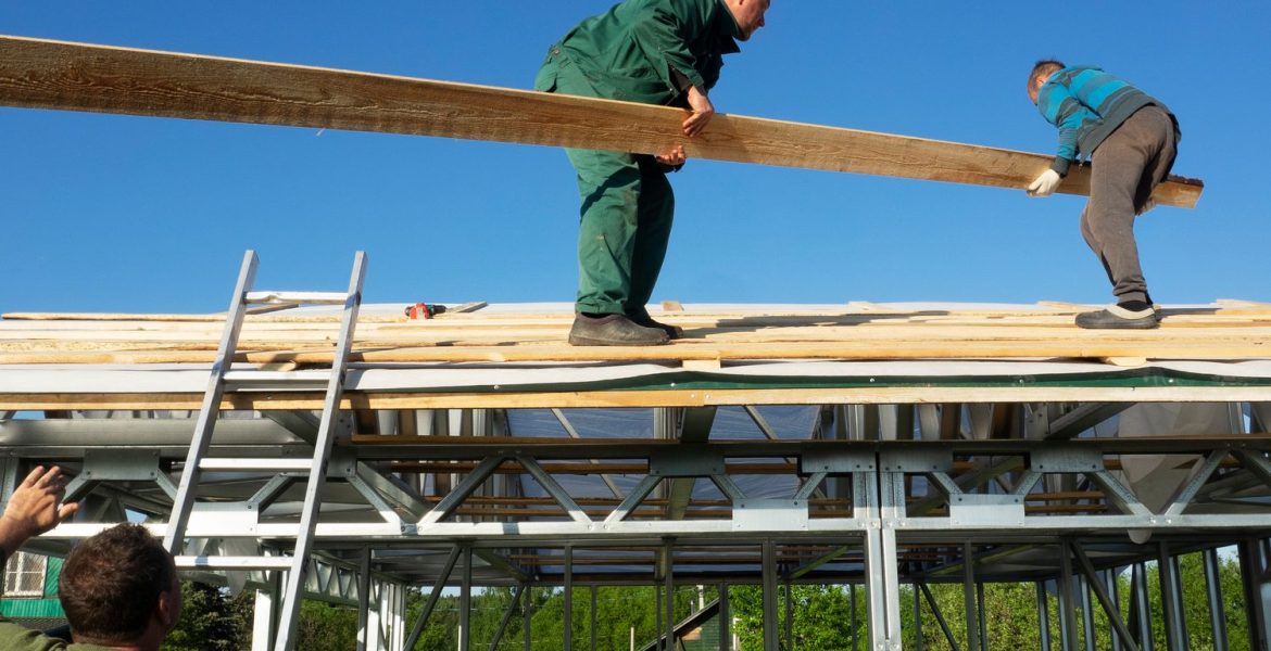 Artisans assemblant l’ossature d’un auvent contre une façade de maison.