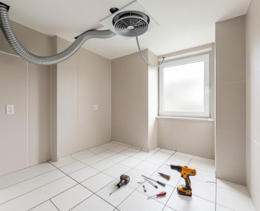 Salle de bains sans fenêtre avec une VMC en cours d’installation au plafond et des joints de carrelage propres.
